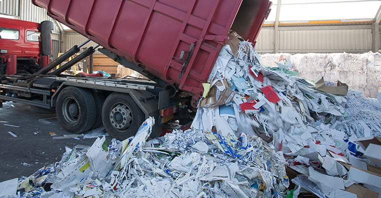 Recyclage industriel : Camion benne et papier déchiqueté Camion rouge déchargeant du papier déchiqueté pour le recyclage industriel.
